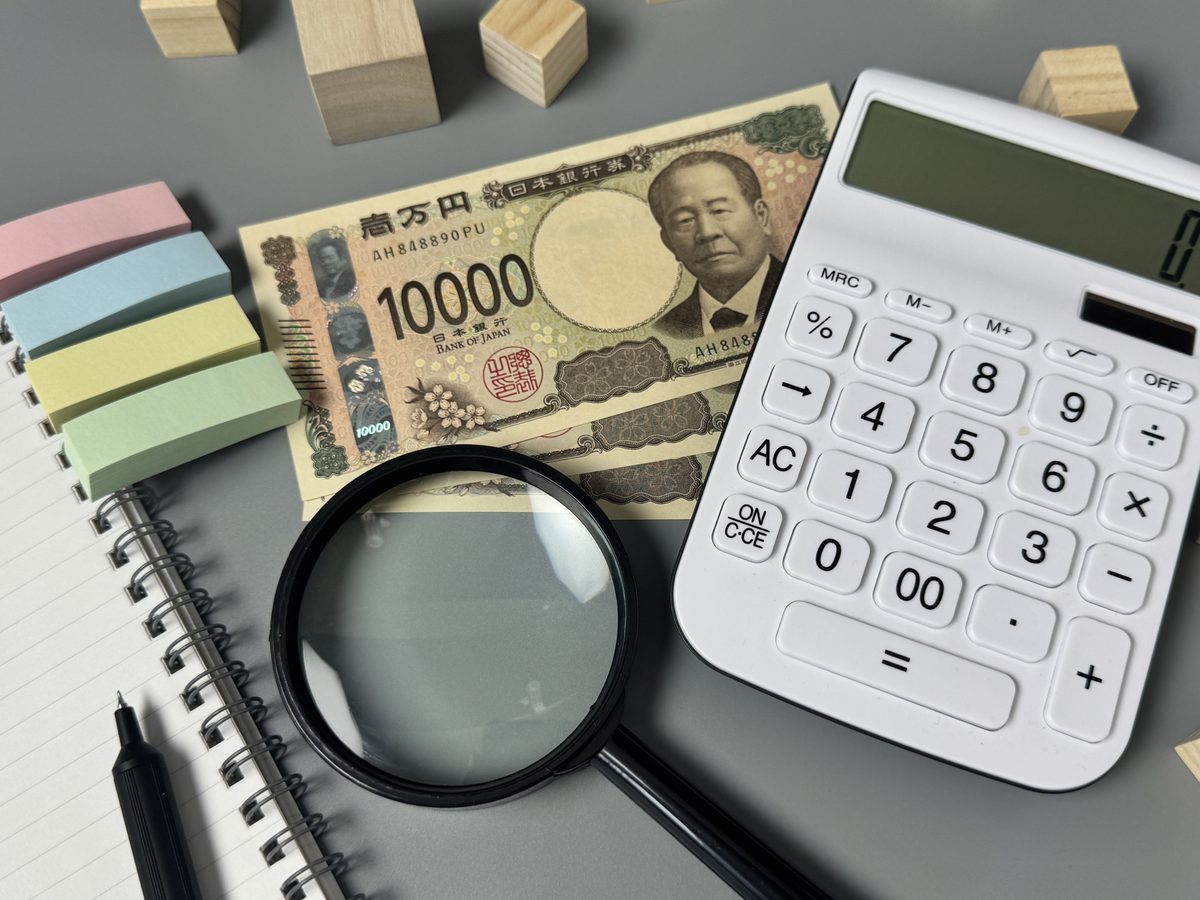 渋沢栄一の一万円札と虫眼鏡、電卓
